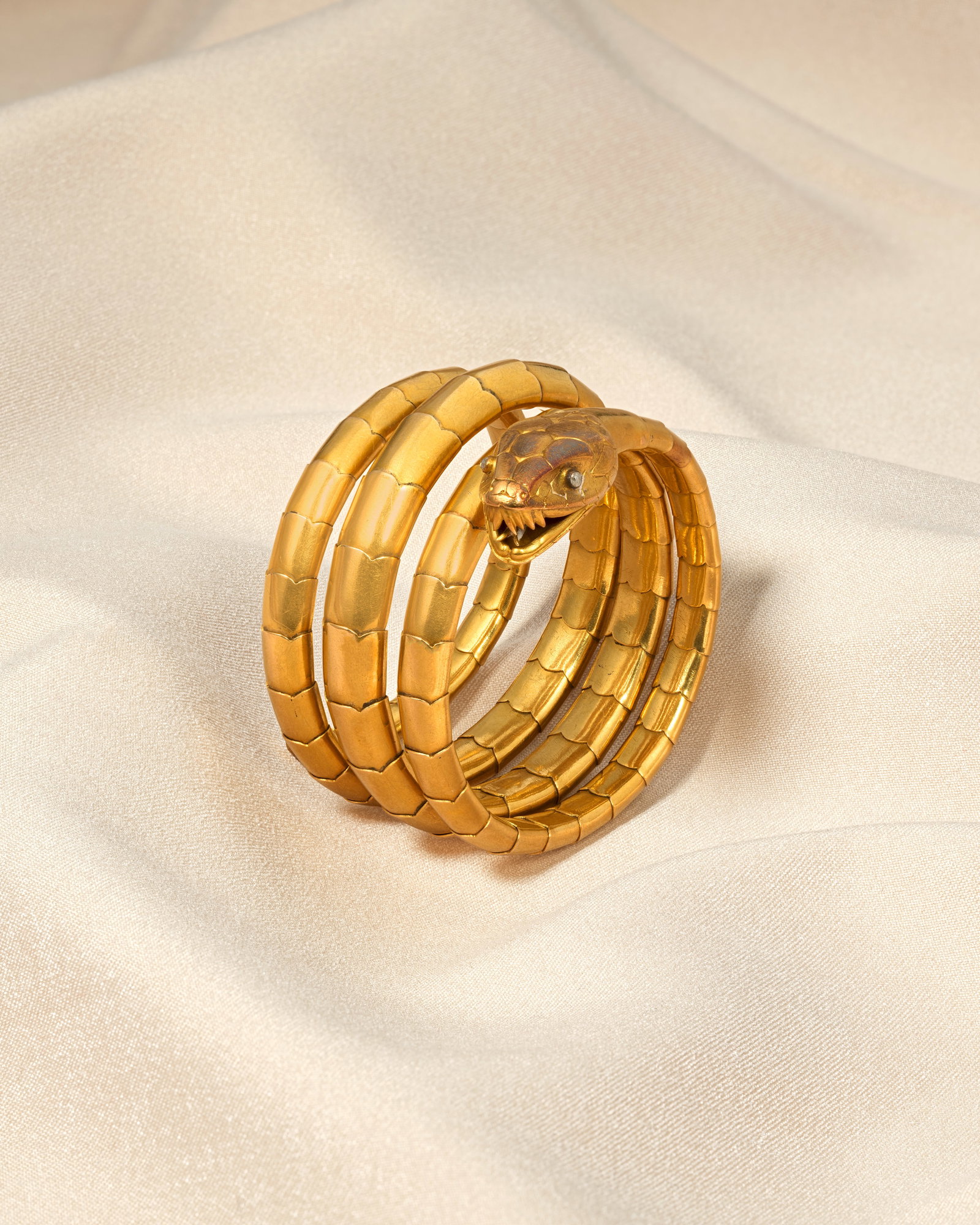 SERPENT BANGLE, CIRCA 1860: SERPENT BANGLE, CIRCA 1860 The coiled snake of sprung design, the head with naturalistic engraving and rose-cut diamond eyes, mounted in gold, inner circumference approx. 15.5cm Footnotes: A Private