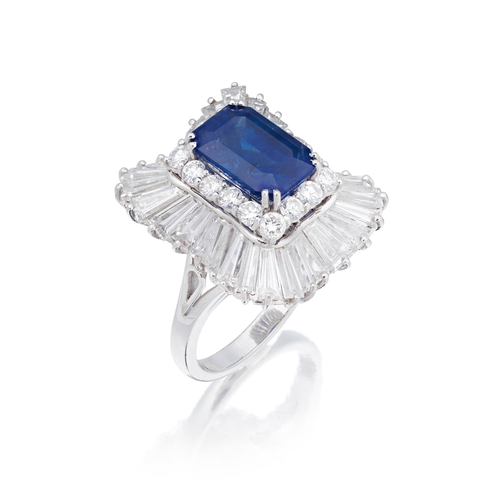 SAPPHIRE AND DIAMOND CLUSTER RING: SAPPHIRE AND DIAMOND CLUSTER RING The step-cut sapphire weighing 4.70 carats, within an undulating border of brilliant and tapered baguette-cut diamonds, diamonds approx. 3.60cts total, ring size appr