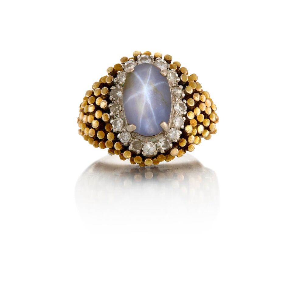 STAR SAPPHIRE AND DIAMOND RING: STAR SAPPHIRE AND DIAMOND RING • 14K yellow gold and white metal consisting of mostly silver • One oval cabochon star sapphire measuring approximately 11.01mm x 7.16mm • Sixteen