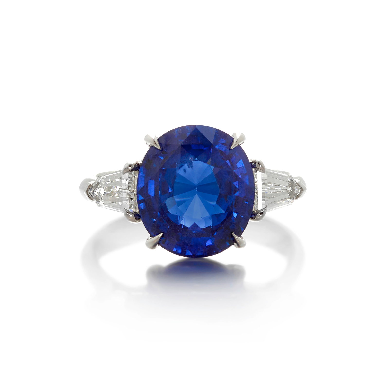 A PLATINUM, SAPPHIRE AND DIAMOND RING: A PLATINUM, SAPPHIRE AND DIAMOND RING Centering an oval-shaped sapphire, flanked by modified tapered-baguette diamonds; estimated sapphire weight 6.95 carats; estimated total diamond weight 0.90