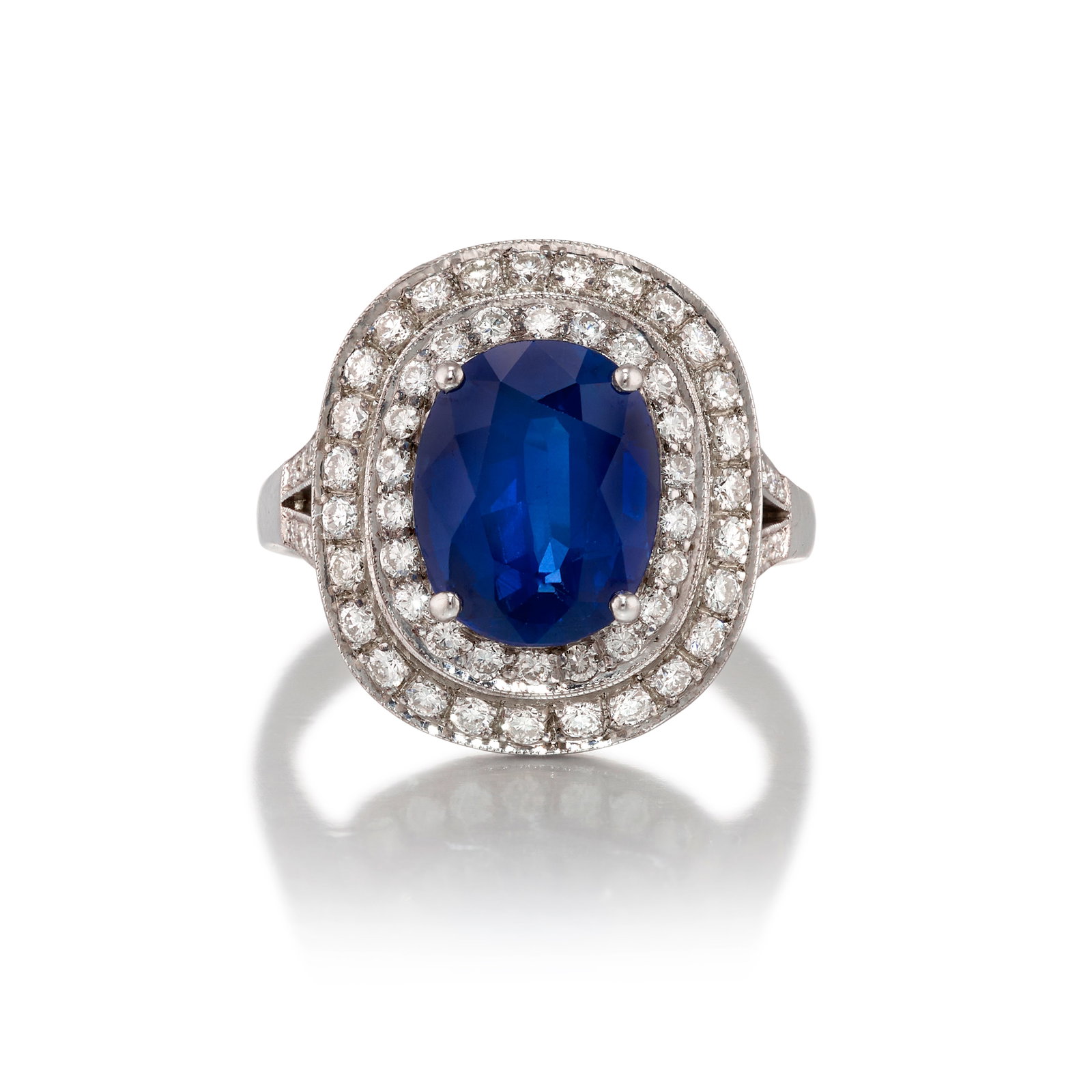 AN 18K WHITE GOLD, SAPPHIRE AND DIAMOND RING: AN 18K WHITE GOLD, SAPPHIRE AND DIAMOND RING Centering oval-shaped sapphire, in a double surround of round brilliant-cut diamonds; estimated sapphire weight 3.05 carats; estimated total diamond weight