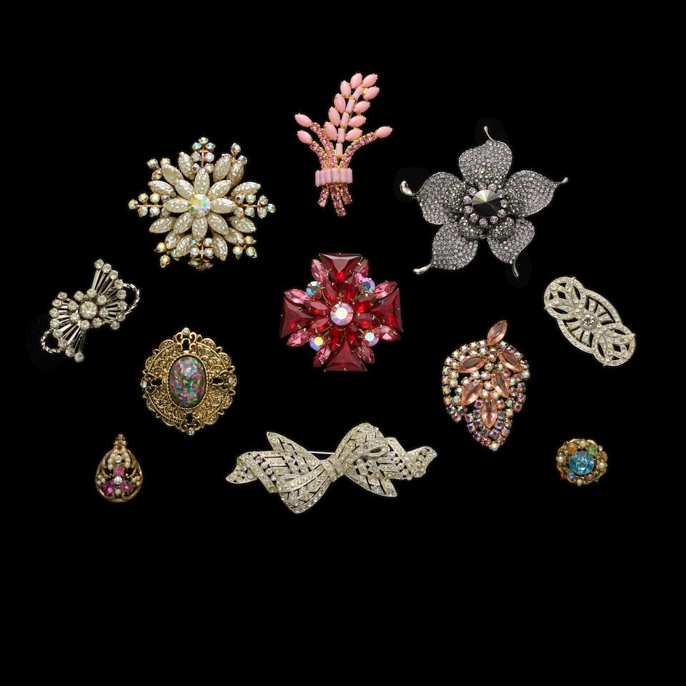 A GROUP OF STAGE-WORN VINTAGE RHINESTONE PINS 1980s: A GROUP OF STAGE-WORN VINTAGE RHINESTONE PINS 1980s Including a pink and red stone cross pin, a grey-tone stone flower pin, and a silver-tone stone elephant pin. Footnotes: Cyndi wore these pins many