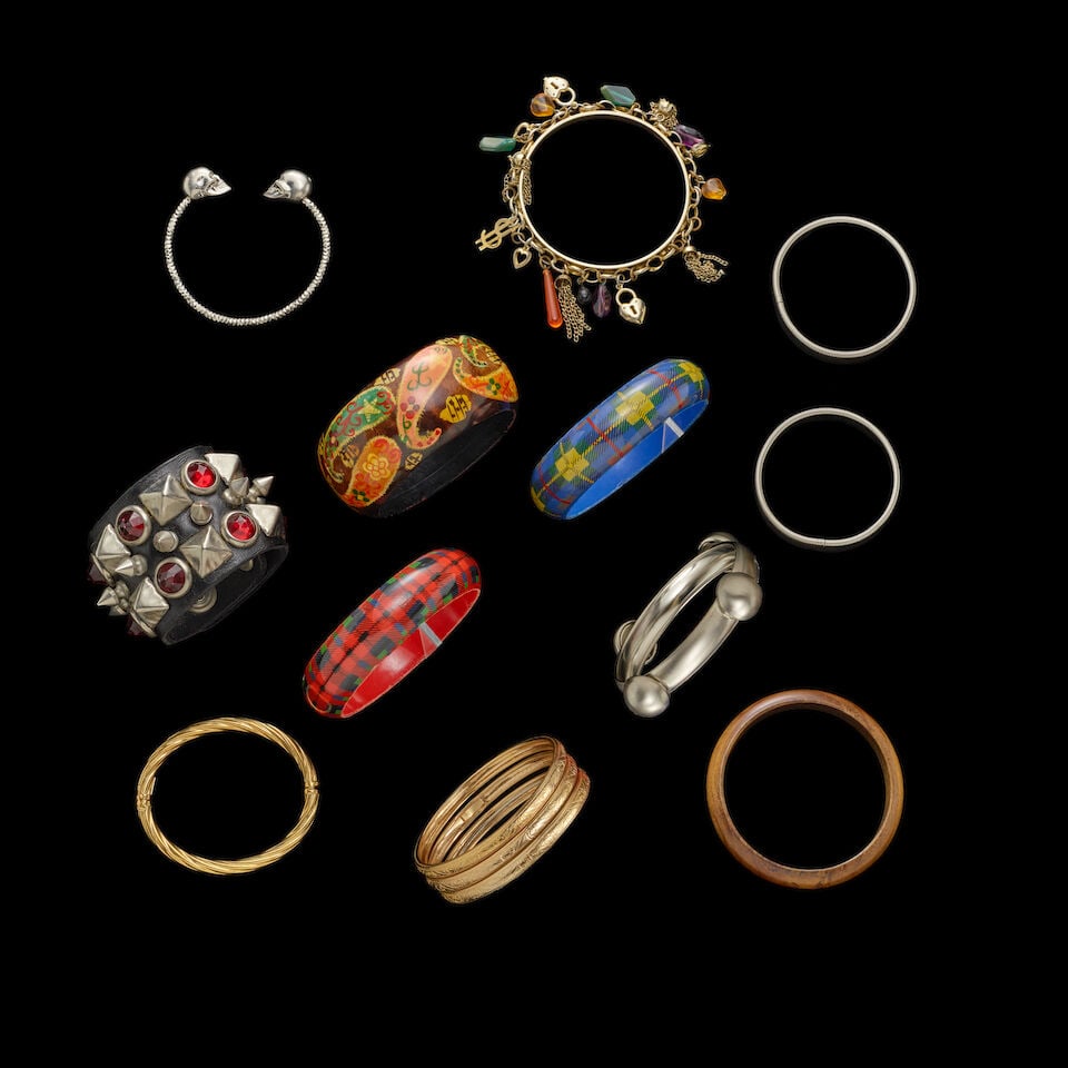 A GROUP OF STAGE-WORN CUFF AND BANGLE BRACELETS 1980s: A GROUP OF STAGE-WORN CUFF AND BANGLE BRACELETS 1980s Including a stud and rhinestone leather cuff bracelet, a bead and charm bangle bracelet, and a silver-tone skull cuff bracelet. This lot is subjec