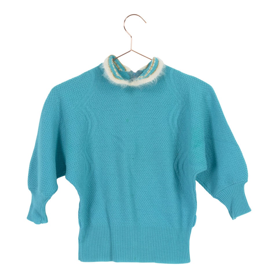 A GROUP OF VINTAGE CARDIGANS AND SWEATERS: A GROUP OF VINTAGE CARDIGANS AND SWEATERS Comprising a red cardigan with a jockey applique, four embellished off-white cardigans, and a white collared blue sweater. (6) This lot is subject to the