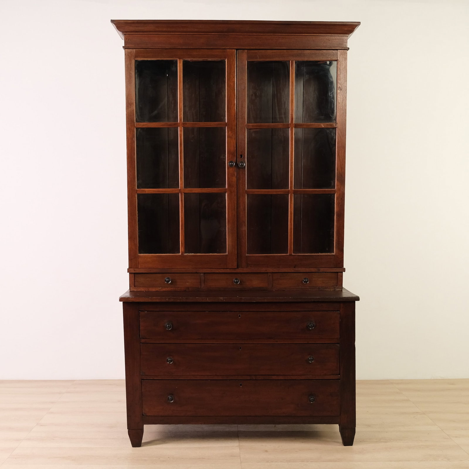 Primitive, Dark-Stained, Pine Cabinet, c. 19th-Century: This 19th-Century primitive pine cabinet features a warm, dark-stained finish, combining generous enclosed storage with a simple, functional country form. A broad molded cornice, sturdy square case, a