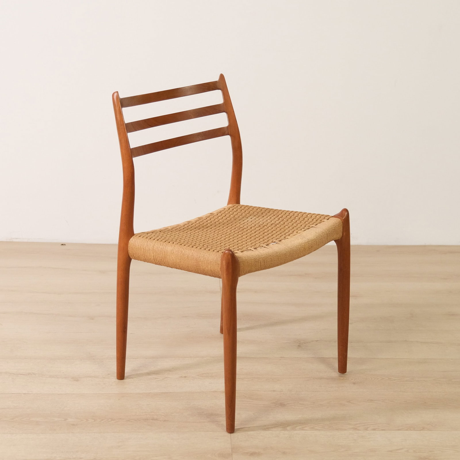 Neils Otto Moller Danish Dining Chair: Classic Danish modern dining chair attributed to Neils Otto Moller, likely Model 79, with a sculptural teak frame and handwoven paper-cord seat. The warm teak frame contrasts beautifully with the