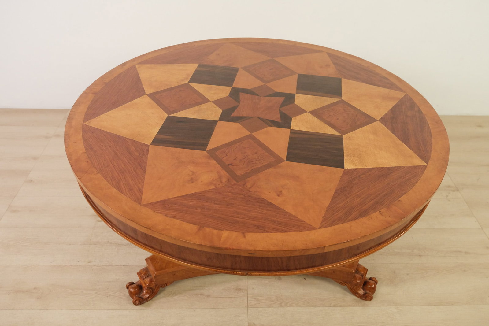 Neoclassical Parquetry Table, c. 1850: Round neoclassical-style dining table featuring a richly figured parquetry top in contrasting? warm and dark-toned woods. The tabletop is centered by a bold geometric star medallion, surrounded by rad
