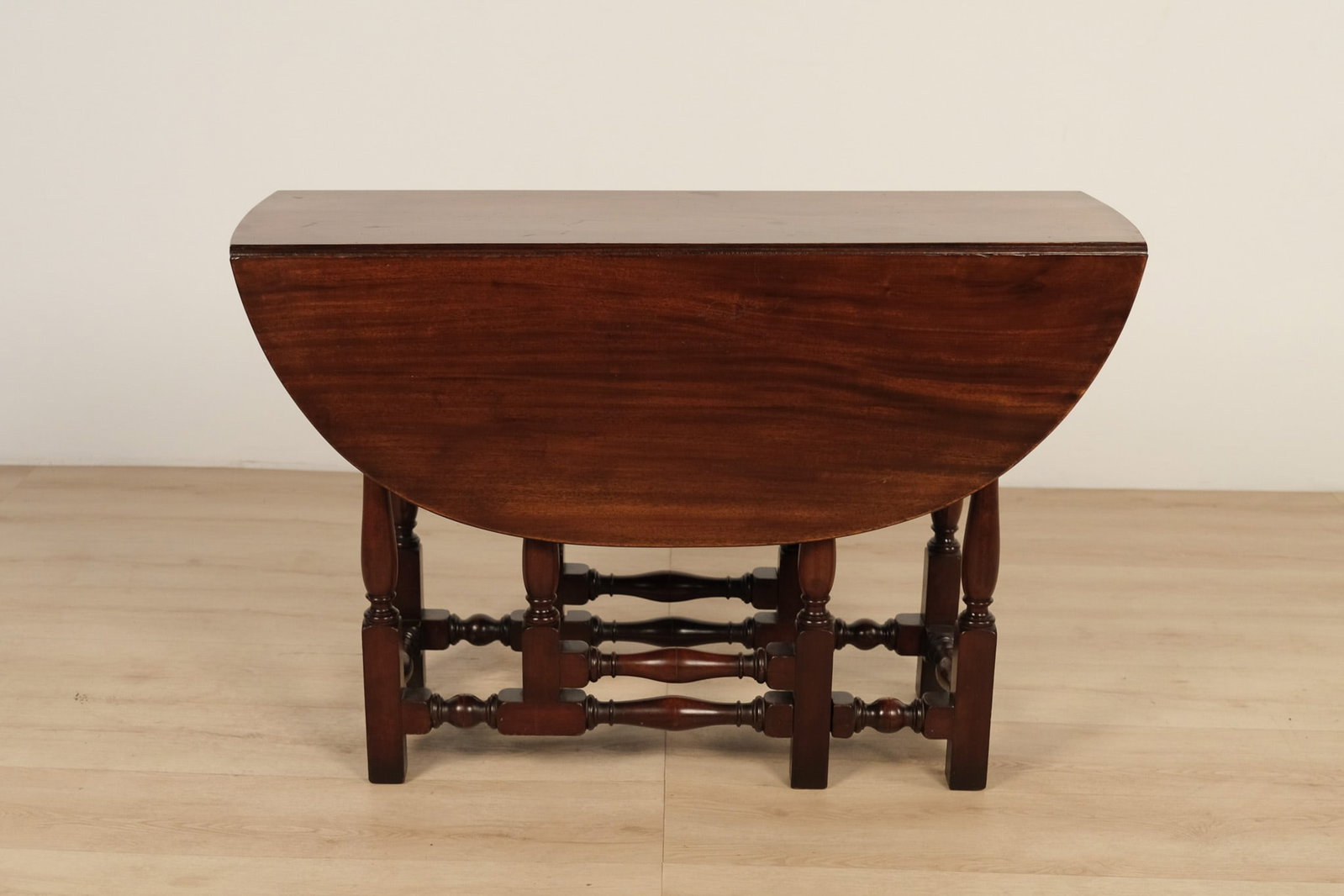 Antique Dark Wood Gateleg Drop-Leaf Table: Antique gateleg drop-leaf table featuring an oval top with hinged drop leaves supported by swing-out gate legs. The base showcases multiple turned baluster legs joined by turned stretchers, all in a