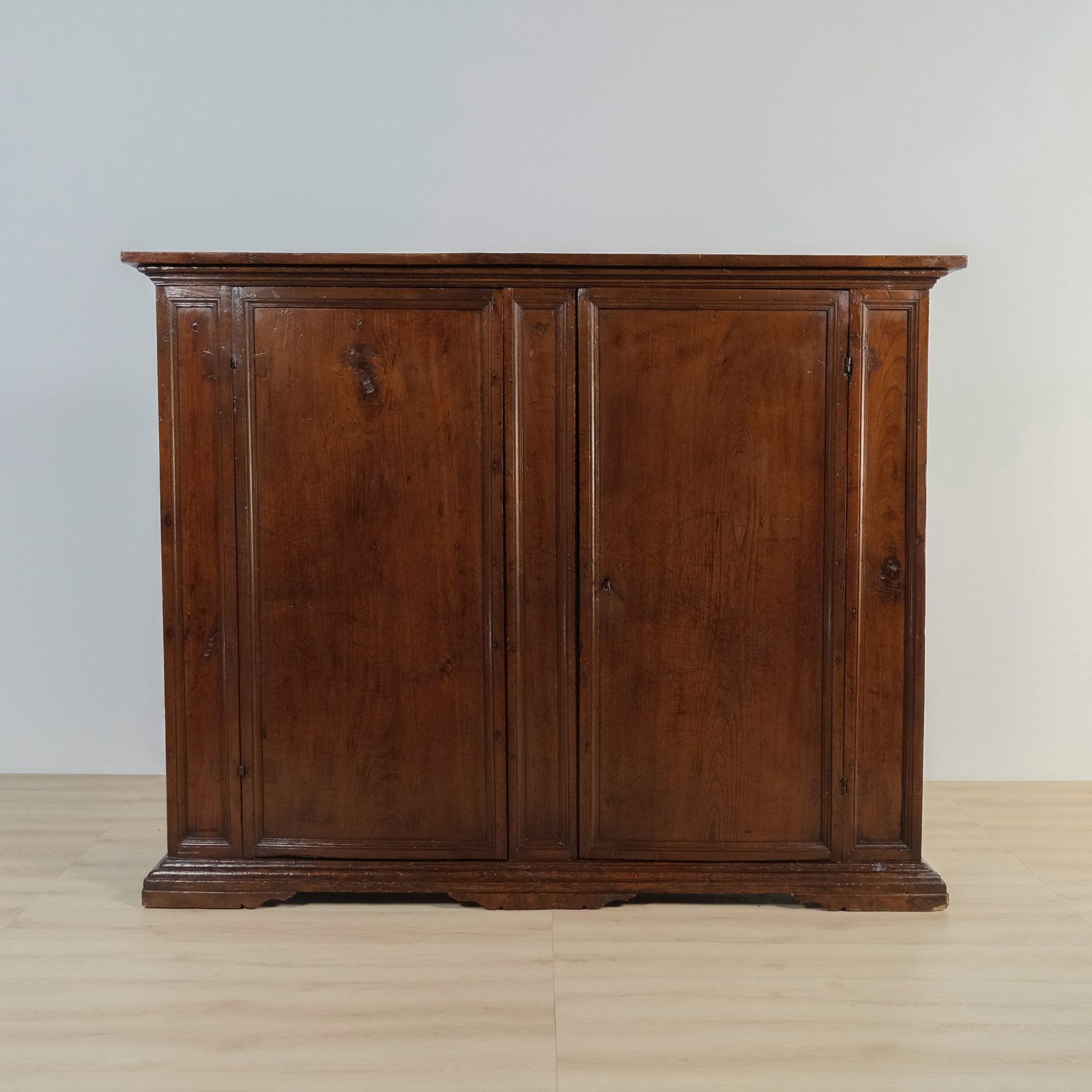 Two Door Solid Wood Credenza: Antique solid wood two-door credenza. The doors framed by narrow raised panels, open to a practical interior divided into two compartments, each fitted with two fixed shelves. A sturdy, honest piece