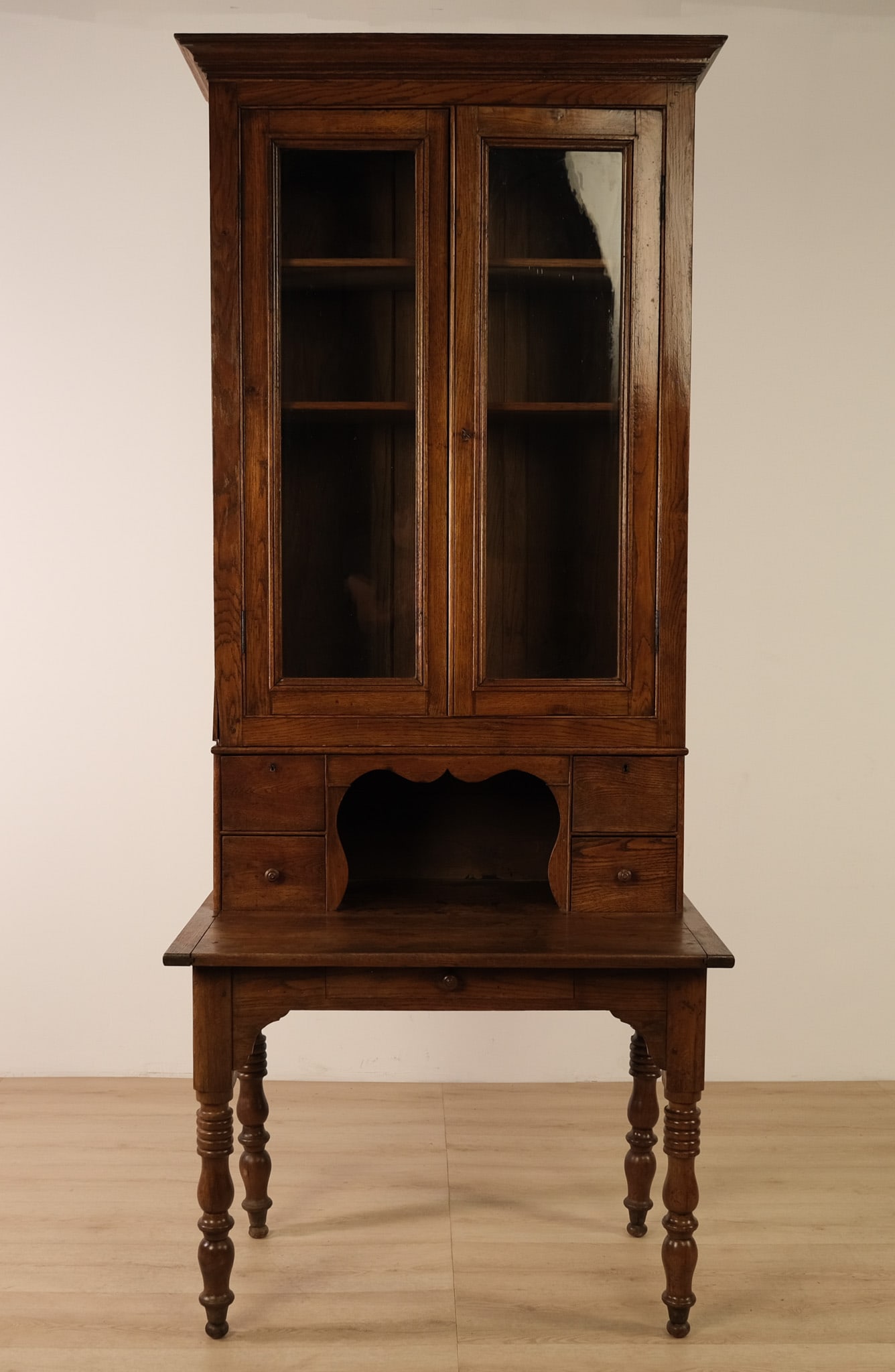 Two Part Oak Cabinet, c. 19th century: A handsome antique oak secretary/bookcase desk in a warm, dark finish. The tall upper cabinet has a molded cornice and two glazed doors opening to a shelved interior. Below, a small hutch section