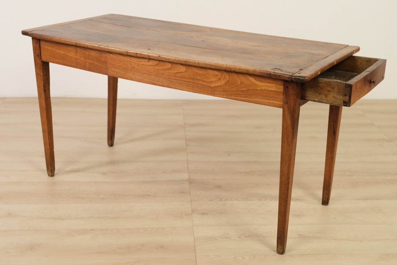 Rustic Walnut Patinated Work Table with Drawer: An antique rustic farmhouse table featuring a single drawer and crafted from warmly patinated hardwood. Its rectangular top is built with several wide planks set inside a raised, molded frame. The