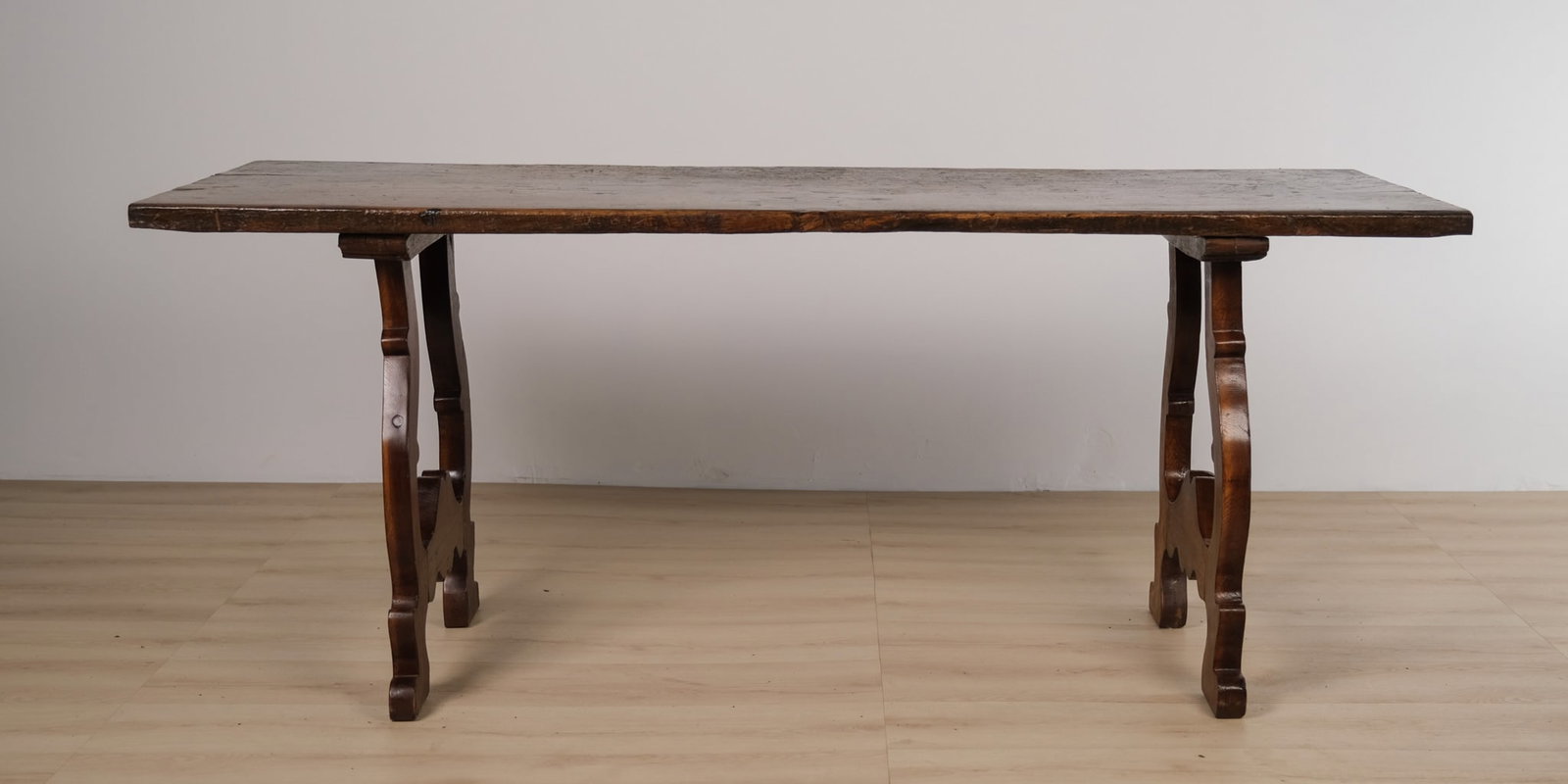 Spanish-Style Lyre Leg Farmhouse Table: Italian imported farmhouse table featuring a substantial rectangular plank top in rich, deeply patinated walnut, supported by shapely lyre-form trestle legs joined to carved scrolled feet. The