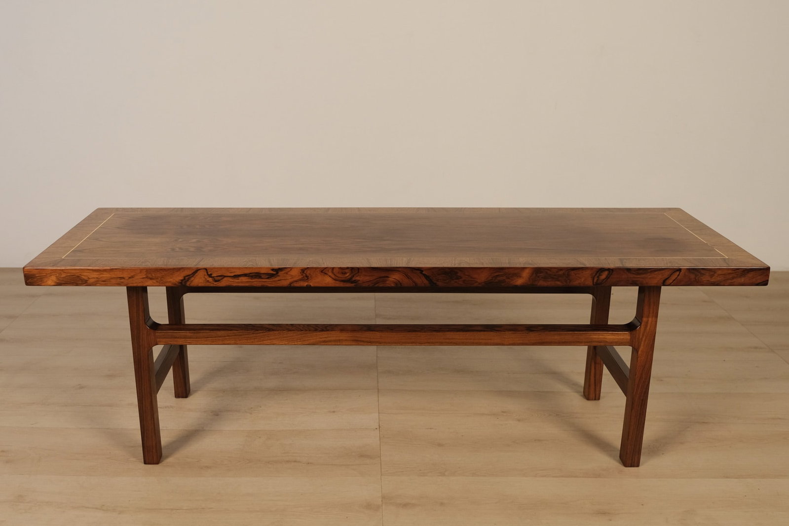 Travail Danois Table, c. 1960: A beautifully crafted Danish "Travail Danois" coffee table, executed in richly figured rosewood with a clean-lined silhouette. The rectangular top is framed by a lighter-toned linear inlay. An