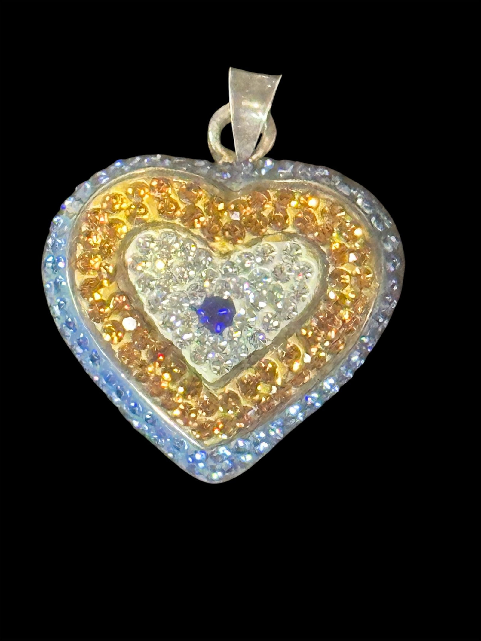 Crystal-encrusted heart shaped pendant: A multi-colored crystal-encrusted heart-shaped pendant with a central blue stone. 6 grams
