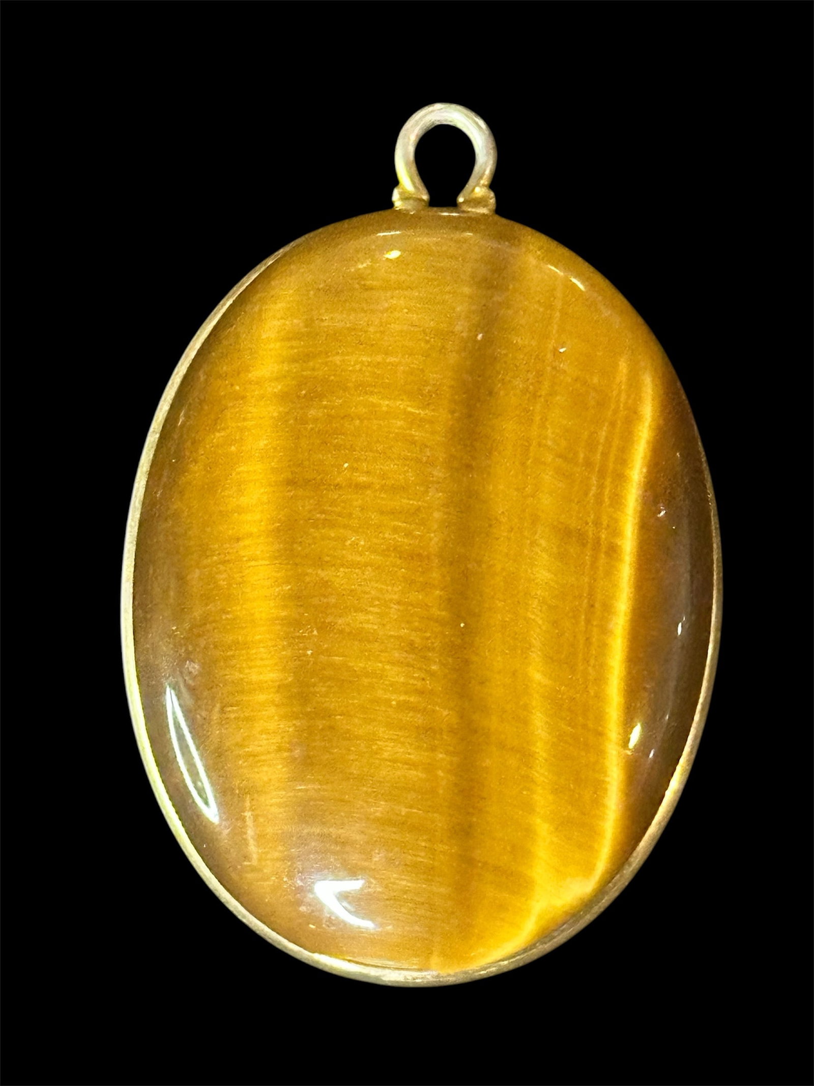 Tiger's eye gemstone Pendant: A polished oval tiger's eye gemstone pendant with a strong "cat's eye shimmer and a simple bezel setting.
