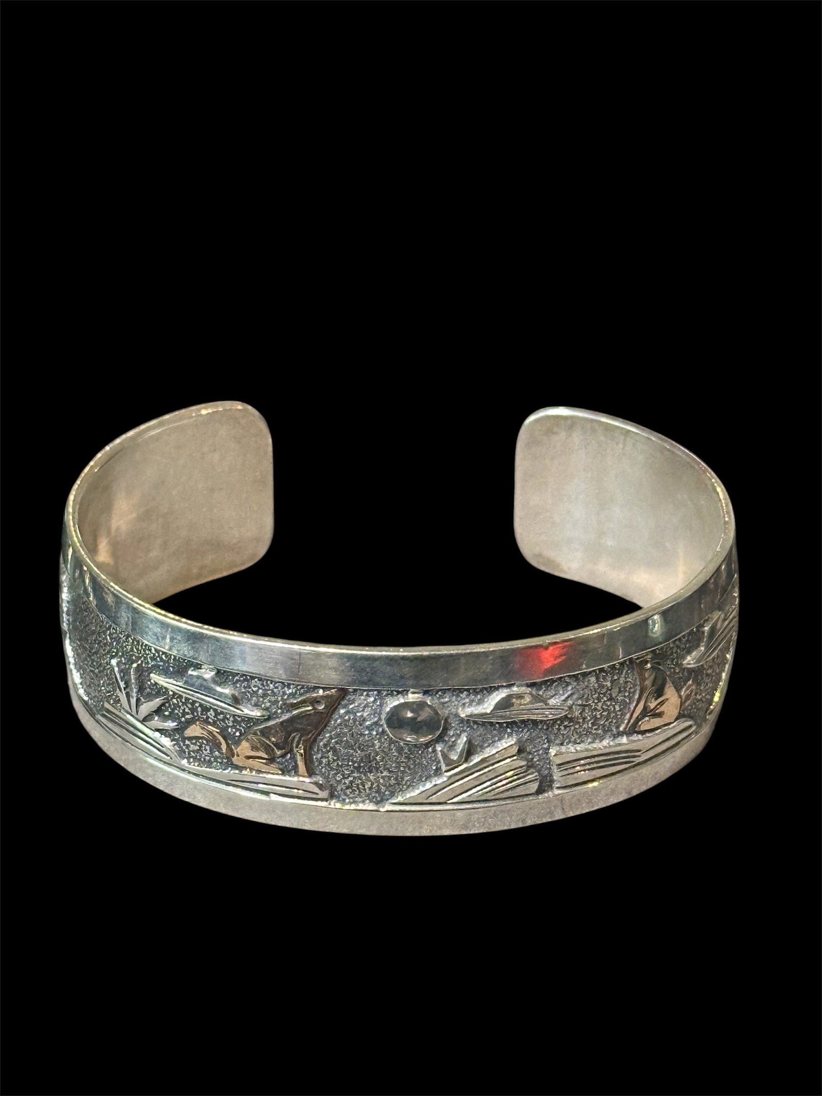 Sterling silver Native American storyteller cuff bracelet with animal motifs.: This is a Native American-style sterling silver storyteller cuff bracelet featuring raised animal motifs and traditional narrative-inspired design elements. The cuff showcases detailed