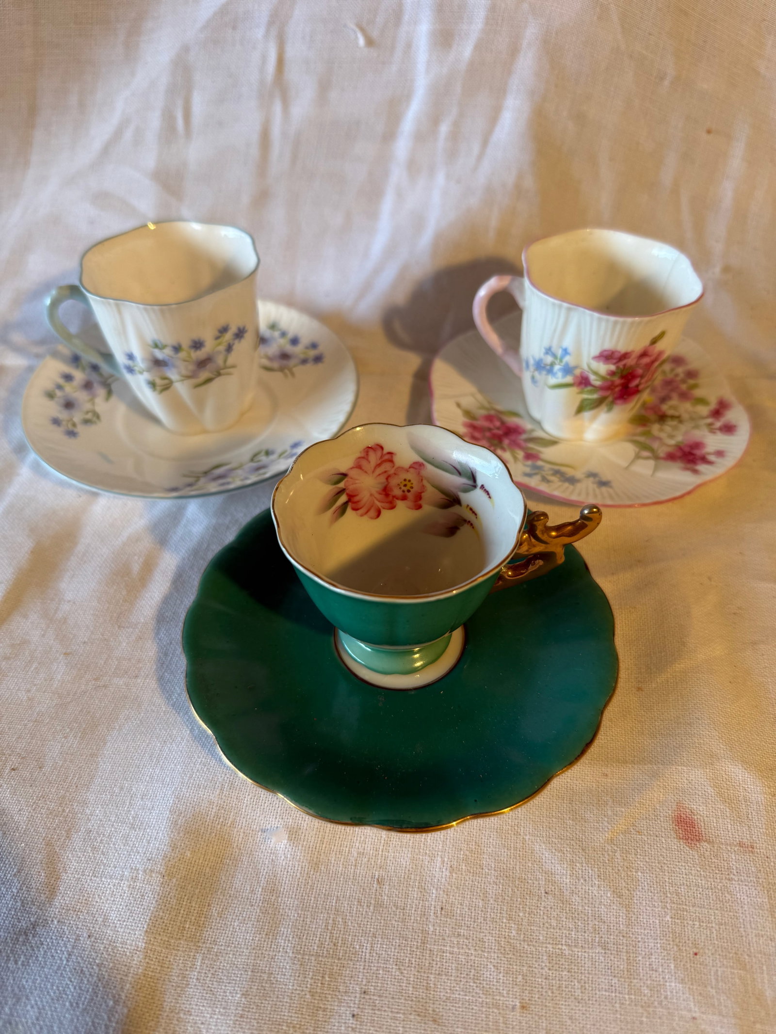 3 Porcelain Demitasse Sets: 2 by Shelley one marked Japan. No chips or cracks. Dimensions: Shelley- 3in H x 5in W. Japan- 2.5in H x 4in W.