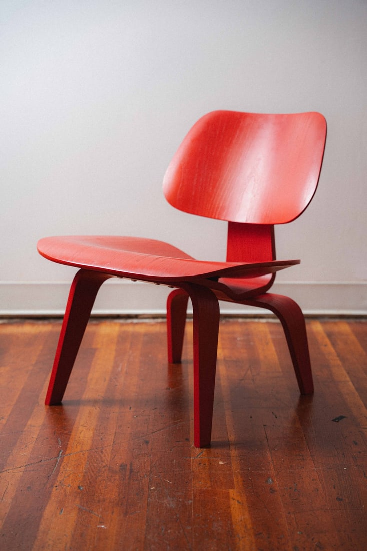 Red Eames LCW by Charles and Ray Eames for Herman Miller: Presenting a red Eames LCW (Lounge Chair Wood) by Charles and Ray Eames, produced by Herman Miller, one of the most celebrated and historically significant chair designs of the 20th century, first