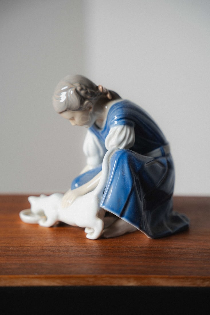 Ingeborg Plockross-Irminger, Royal Copenhagen Bing & Grondahl Porcelain Figurine #1745, Girl with: Presenting a Royal Copenhagen / Bing & Grøndahl porcelain figurine #1745, "Girl with Cat Drinking Milk," sculpted by the celebrated Danish artist Ingeborg Plockross-Irminger, who was among the fi