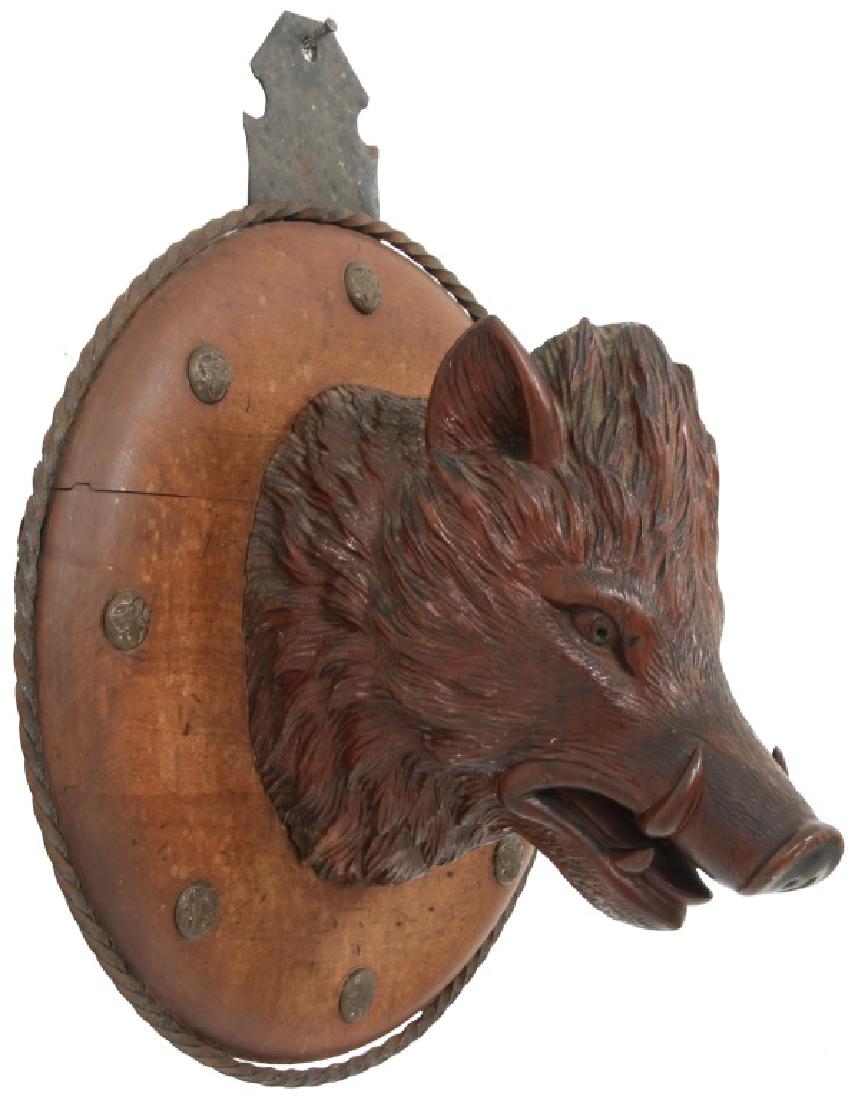 Black Forest Carved Boar Head: Black Forest Carved Boar Head. Excellent figural carved black forest boar's head mounted on a walnut back panel with twisted wrought iron trim and rosettes; in excellent condition, original finish. 18