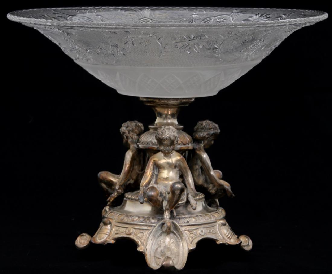 Silver Plated & Glass Center Figural Bowl: Silver Plated & Glass Center Bowl. Silver plated base with 3 putti figures seated on a platform with 3 feet and turned center stem; with a 12" diameter pressed glass bowl with swirling filigree and di