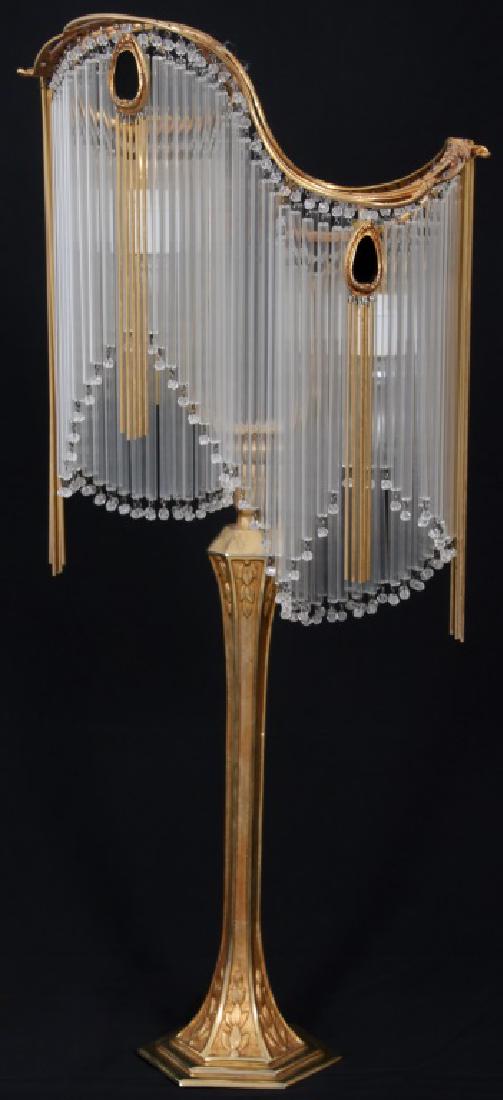 After Hector Guimard Art Nouveau Table Lamp: After Hector Guimard Art Nouveau Table Lamp. Gilt bronze base has an hexagonal stepped platform with long stem having relief leaves at the top and bottom; a series of long hollow glass tubular prisms