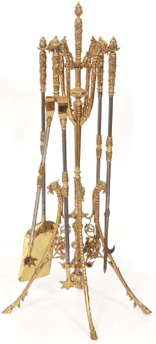4 Piece Brass Fireplace Set with Stand: 4 Piece Brass Fireplace Set with Stand. Gilt brass filigree decorated stand has a relief decorated turned center stem with concave legs having griffin heads at the top and hoofed feet; 4 griffin head 