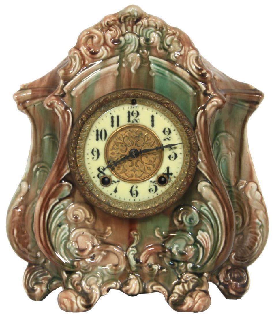 Gilbert "La Loie" Majolica Mantle Clock: Gilbert "La Loie" Majolica Mantle Clock. 4" porcelain dial with brass center has black hour numbers, black hands and a hinged brass door bezel with beveled crystal; silvered brass 8 day spring driven