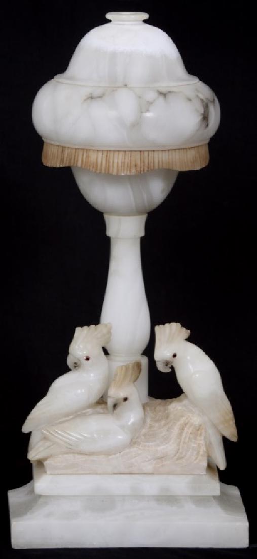 Alabaster Lamp w/ 3 Cockatiels: Alabaster Lamp w/ 3 Cockatiels. Alabaster cockatiel lamp with three birds on the base having glass eyes and a dome shaped shade with faux fringe. Top of shade shows discoloration due to heat. Dimensio