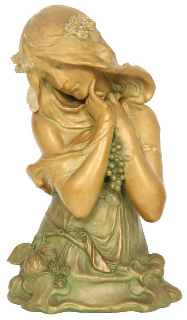 Teplitz Amphora Porcelain Bust: Teplitz Amphora Porcelain Bust. Amphora porcelain bust of a beautiful Art Nouveau woman draped in a shawl, holding a grape cluster between her arms and various other fruit at her hip, decorated in sha