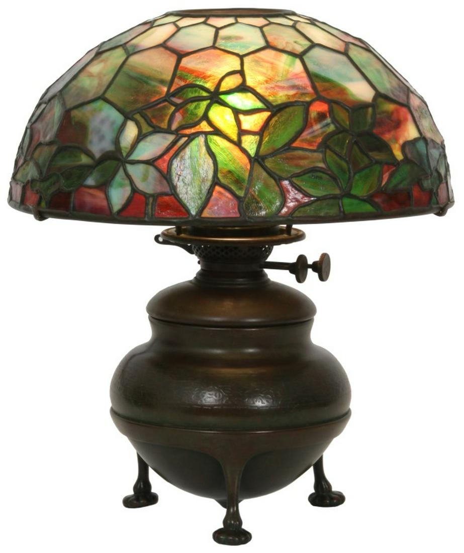 Tiffany Studios Woodbine Table Lamp: Tiffany Studios Woodbine Table Lamp. 14 in. diameter Woodbine leaded shade has green striated to deep red glass; signed "Tiffany Studios, New York, 1423 - 2." On a bronze, three-footed bulbous oil can