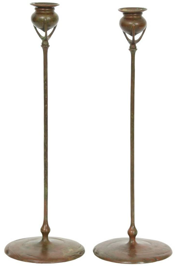 Two Tiffany Studios Bronze Candlesticks: Two Tiffany Studios Bronze Candlesticks. Having a round foot, long thin stem and three prong candle holder mounts. The taller is signed "Tiffany Studios, New York, D800"; the shorter is signed "Tiffan
