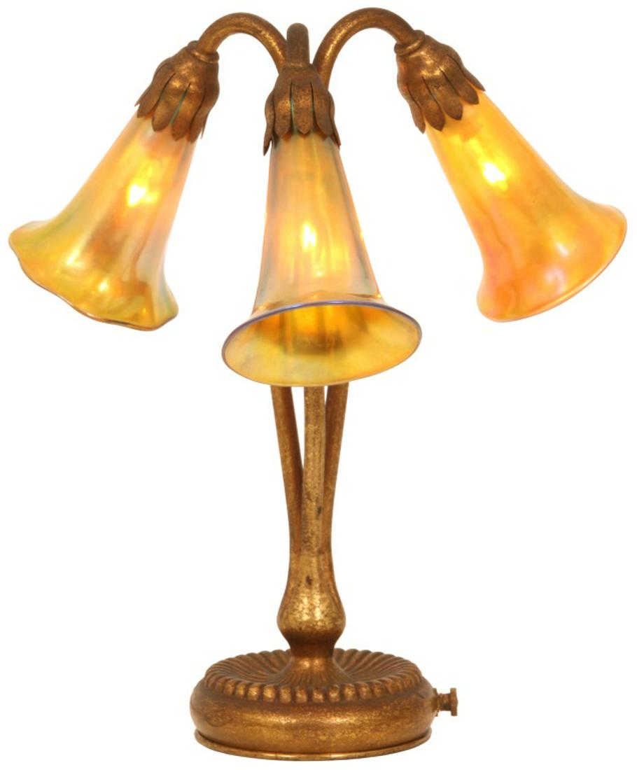 Tiffany Studios 3 Light Lily Lamp: Tiffany Studios 3 Light Lily Lamp. The gold dore bronze base has a reeded platform which is concave in the center, a cluster branches up with 3 floral stems in a serpentine form, secured at the top th