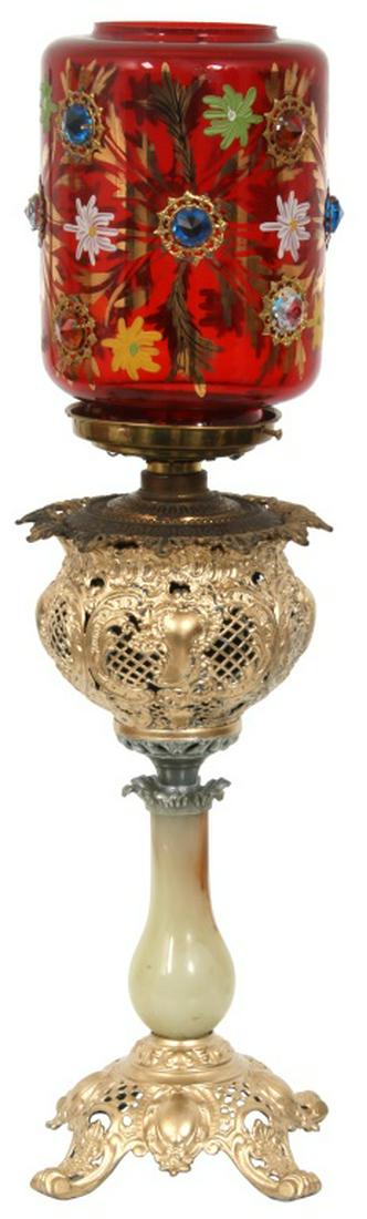 Piano Lamp with Jeweled Shade: Piano Lamp with Jeweled Shade. The cranberry glass jeweled shade has enamel decorated yellow, green and white flowers, gilt filigree, and jeweled facets with gilt brass borders; 9 3/4 in. high x 7 in.
