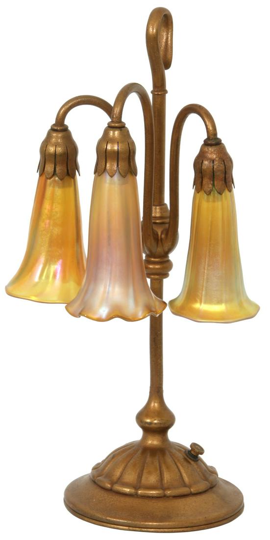 Tiffany Studios Three Light Lily Lamp: Tiffany Studios Three Light Lily Lamp. Dore bronze lamp base with long center post, hooking at the end to form a handle, has 3 stems branching out from the center which curve upward and forward with f