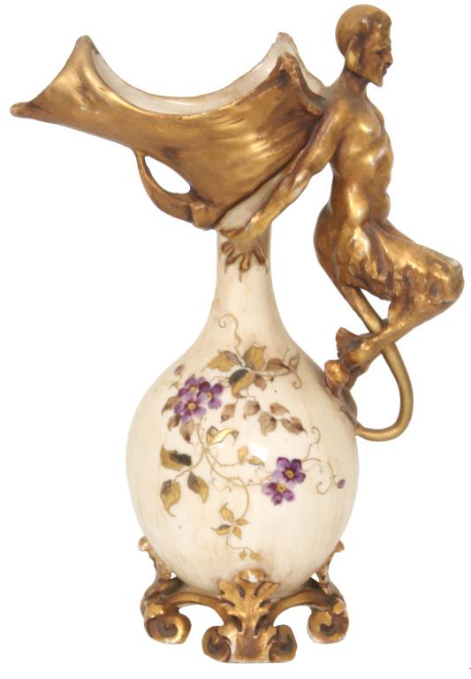 Teplitz Amphora Devil Handled Ewer: Teplitz Amphora Devil Handled Ewer. The ewer has a bulbous body decorated with flowers, leaves and vines against a cream-colored background; has a gilt decorated figural devil handle, unusual shaped s