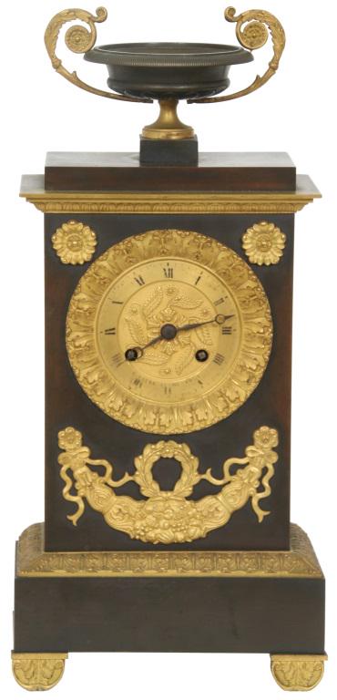 French Empire Silk Thread Mantle Clock: French Empire Silk Thread Mantle Clock. Gold gilt embossed dial with ormolu gilt highlights & urn finial, silk thread movement striking on a bell. Dimensions: 14 in. high x 3.5 in. deep x 6.75 in. wid