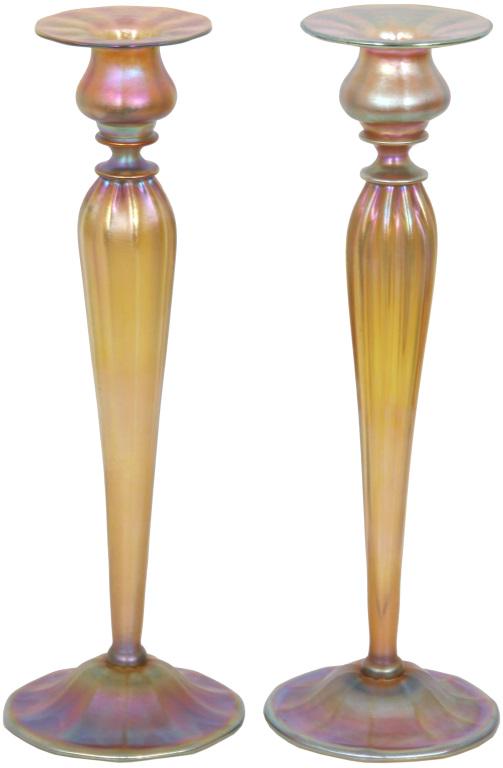 Pair of Tiffany Studios Favrile Glass Candlesticks: Tiffany Studios Favrile glass candlesticks with gold to rose colored iridescence, the tapered stems and bases have a ribbed design. Both are signed on the underside, "L.C.T. Favrile 1826." In good con