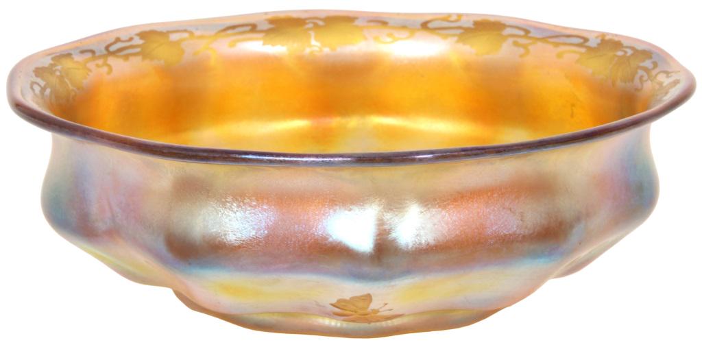 Tiffany Studios Favrile Glass Intaglio Cut Bowl: Tiffany Studios gold iridescent Favrile glass bowl has a ribbed form with pinched neck and wavy flaring rim. Intaglio cut leaf and vine patterns border the top of the rim and the base of the interior;