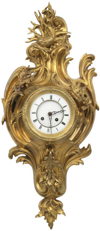 French Gilt Bronze Cartel Clock: French cartel clock in gilt bronze with rococo style filigree decoration and a figural dolphin at the upper cartouche; 8 day French brass movement is running & striking. Dimensions: 25 in. high x 10 i