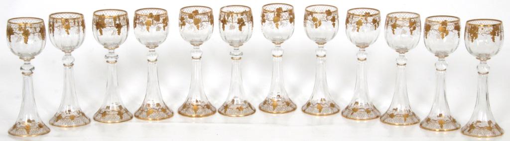 Set of 12 Hock Wine Glasses: The set of 12 hock wine glasses have gilt decorations of grapes & vines on a trellis with clusters hanging throughout. Dimensions: 7.75 in. high x 3 in. diameter.