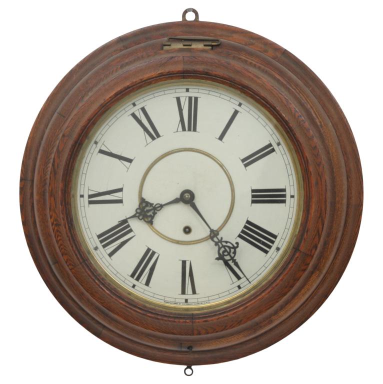 Waterbury Oak Gallery Clock: Waterbury Clock Co. Gallery clock with Roman hour numerals and fancy pierced hands oak case movement signed "Waterbury Clock Co., U.S.A." early 20th century 18 in. diameter x 4 1/2 in. deep The absenc