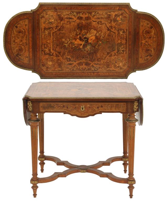French Inlaid Drop Leaf Table: French drop leaf table has decorated inlays with filigree and a center panel with musical instruments and musical motifs on each corner; the apron has incised carving with bronze mounts on each corner