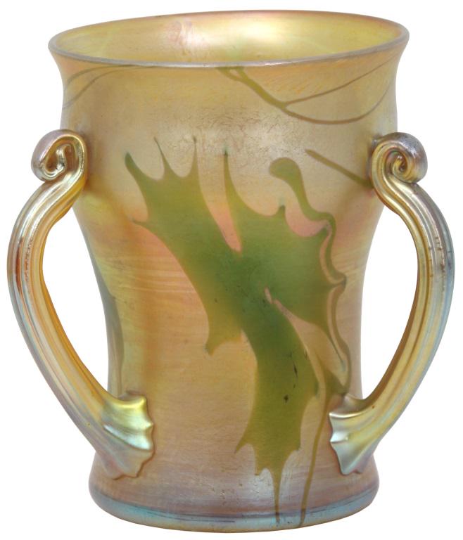 Tiffany Studios Favrile Glass Loving Cup: Tiffany Studios gold iridescent Favrile glass loving cup has three fluted, coiled handles and the body has a green leaf and vine design. Signed on the underside, "L. C. Tiffany - Favrile, 3633D." Very