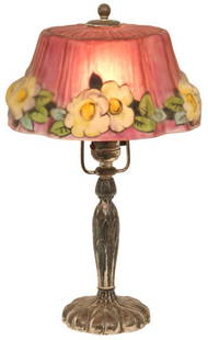 Pairpoint Puffy Boudoir Lamp: Pairpoint puffy boudoir lamp has a Stratford shade decorated with dogwood flowers set against a cranberry background. Supporting the shade is a silvered base with palm leaf motifs; signed on the