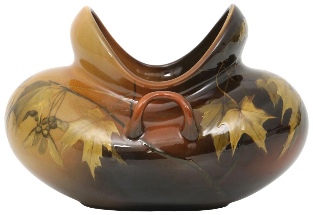 Rookwood Pottery Iris Vase: Rookwood Pottery vase is in a bulbous form with an open top and is decorated with maple tree leaves and samaras; set against a brown to yellow shaded background. Marked on the underside with flame mar