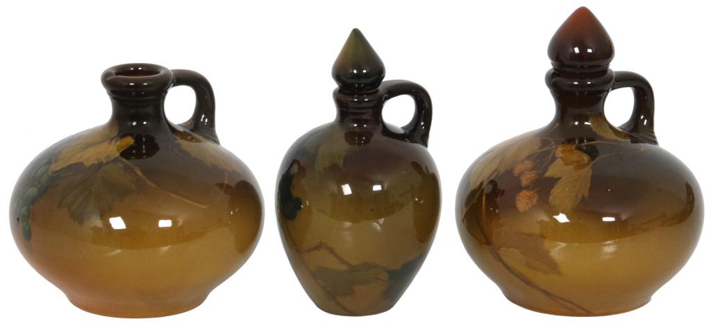 Three Rookwood Pottery Jugs: Three Rookwood Pottery jugs have a standard glaze and are decorated with floral, foliate and berry cluster designs. 1) Dated 1894, numbered 675, signed "MAD" for Matt Daly, 5 3/4 in. high x 6 1/4 in. 
