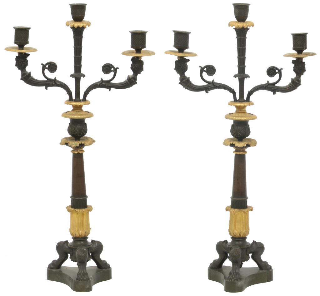 Pair of Empire Bronze Candelabra: Pair of Empire gilt and patinated bronze candelabra have three claw foot supports, acanthus decorated turned stem with center candle holder and two arms with figural female heads on either side facing