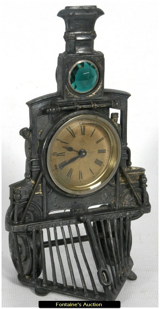 Ansonia Novelty No. 44 Train Desk Clock: Ansonia Novelty No. 44 Train Desk Clock. The clock represents a frontal view of a train engine, showing the conductors on both sides and a jeweled headlight; centered is a 2" paper dial with black spa