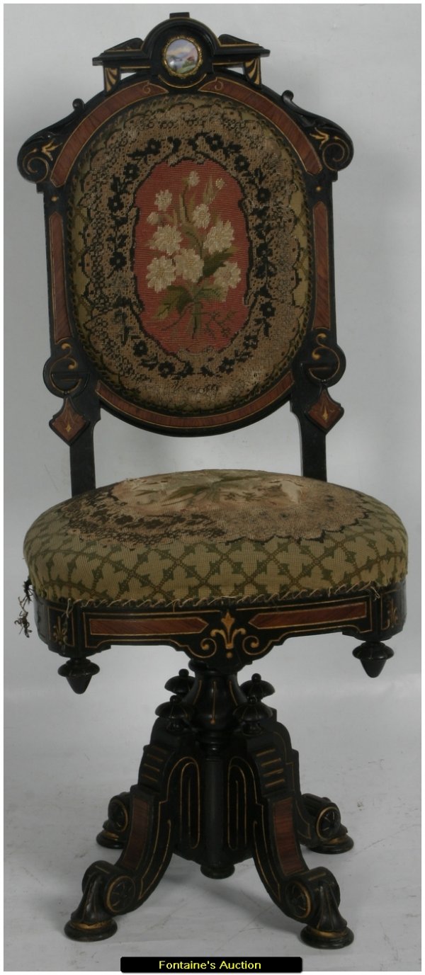 VICTORIAN STOOL: Ebonized Swivel Seat Stool, attr. Pottier & Stymus. Has an ebonized finish with gilt incising and walnut panels, a carved crest on the back centered with a small scenic porcelain medallion, drop finia